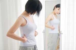 ผู้หญิงกำลังกังวลกับไขมันส่วนเกินบริเวณหน้าท้องที่ทำให้ไม่มั่นใจ