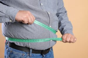 A man struggling with the measuring tape for his belly fat